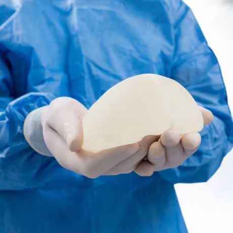 Doctor holding breast implant - breast augmenation menu
